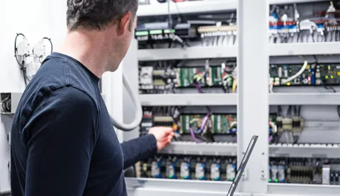Electrician working on electronics cabinet