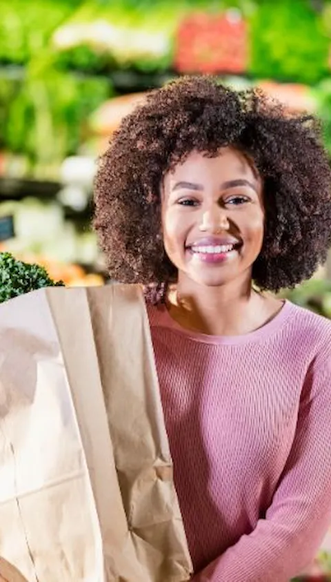Kvinna i snabbköp med påse med grönsaker