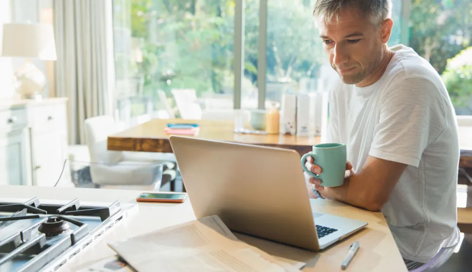 Man drinking coffee and working on laptop