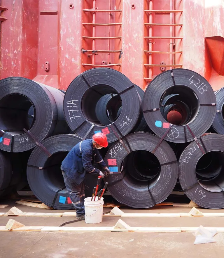 Worker fastening steel coils in cargo hold